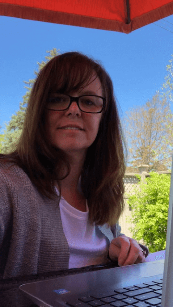 Heather works at her laptop on a sunny backyard patio