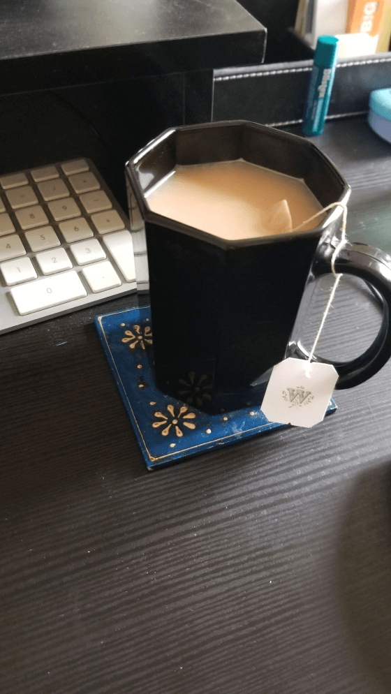 Cup of milky tea beside a keyboard
